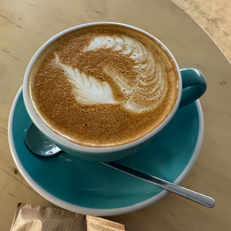 Cappuccino with a swan in latte art in a teal cup